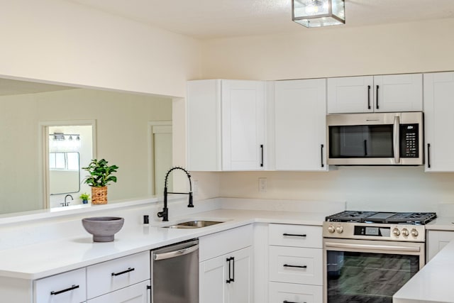 kitchen featuring stainless steel appliances, white cabinetry, a sink, and a peninsula