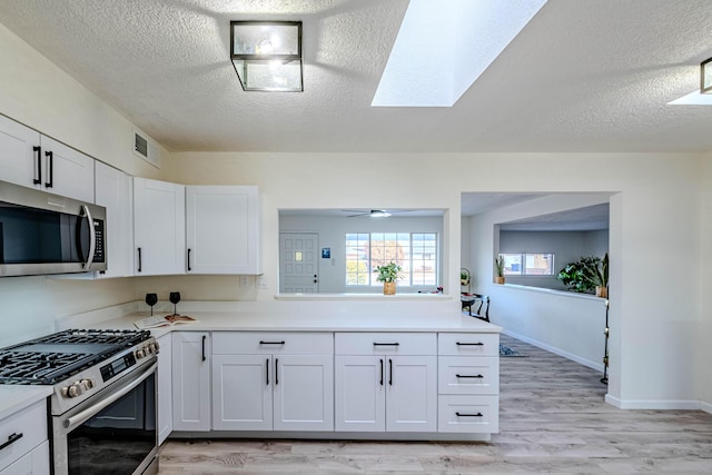 kitchen featuring light countertops, visible vents, light wood-style flooring, appliances with stainless steel finishes, and white cabinets