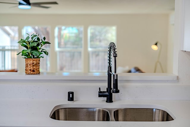 interior details with ceiling fan, light countertops, and a sink