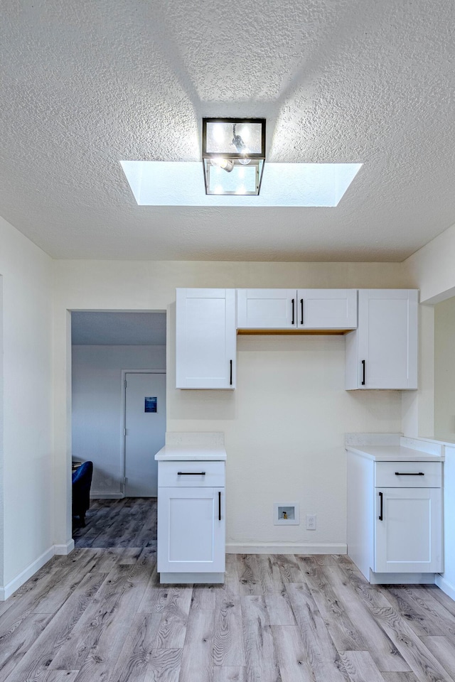 kitchen with light wood-style floors, light countertops, and white cabinetry