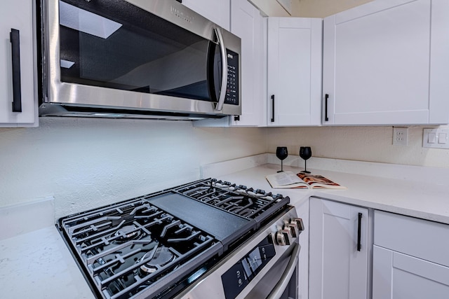 kitchen featuring appliances with stainless steel finishes, light countertops, and white cabinets