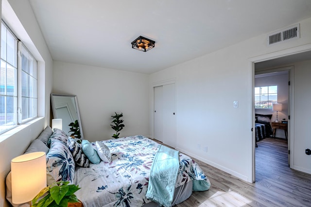 bedroom with baseboards, a closet, visible vents, and wood finished floors