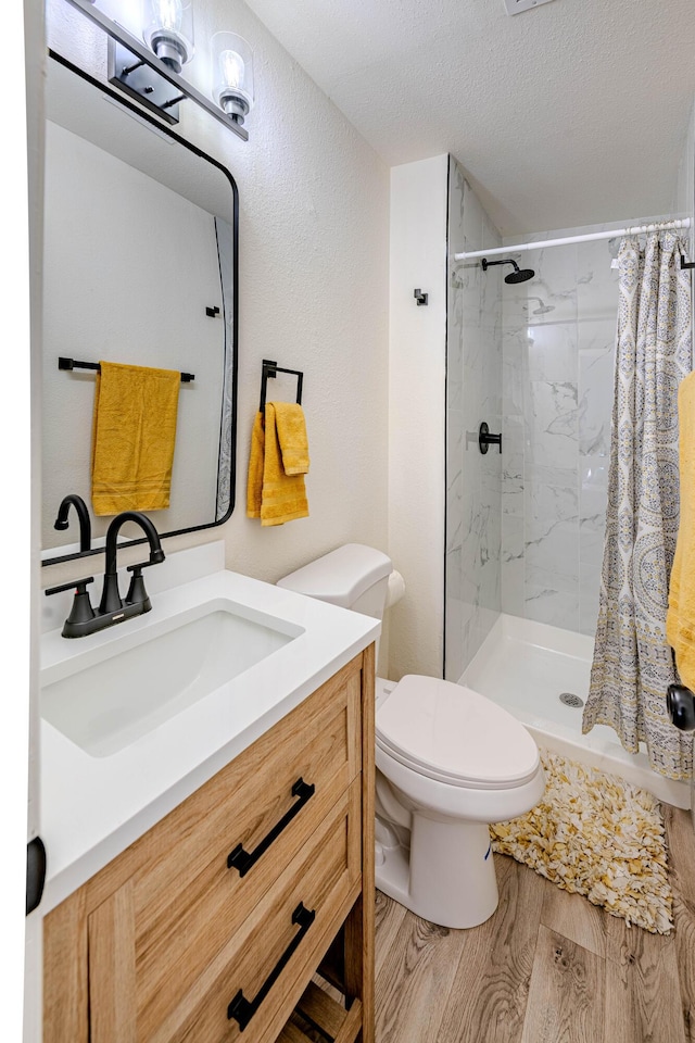 bathroom with toilet, a stall shower, a textured ceiling, and wood finished floors