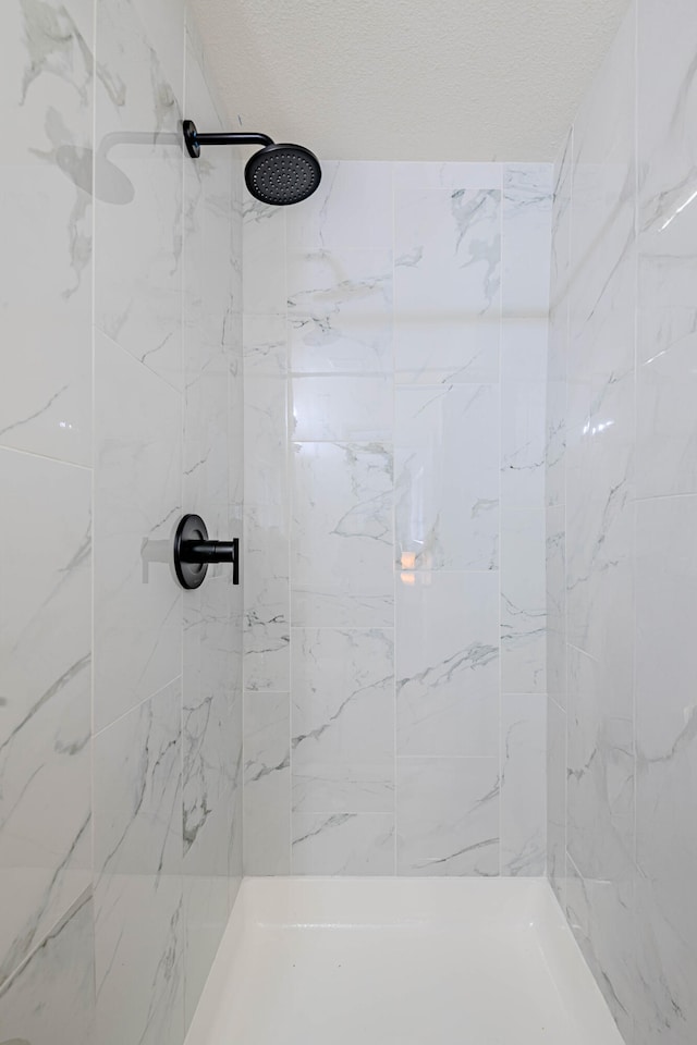 full bath featuring tiled shower and a textured ceiling