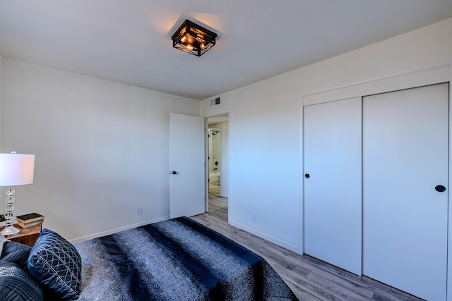 bedroom featuring a closet, wood finished floors, visible vents, and baseboards