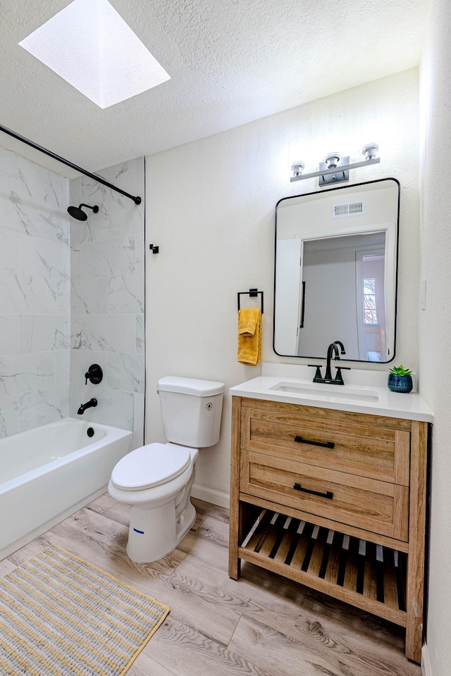 bathroom with a skylight, toilet, vanity, a textured ceiling, and wood finished floors