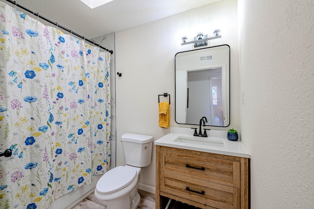 full bathroom featuring toilet, a textured ceiling, and vanity