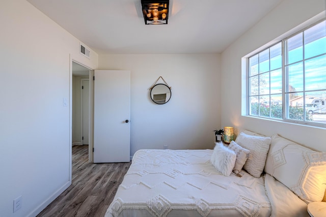 bedroom featuring baseboards, visible vents, and wood finished floors