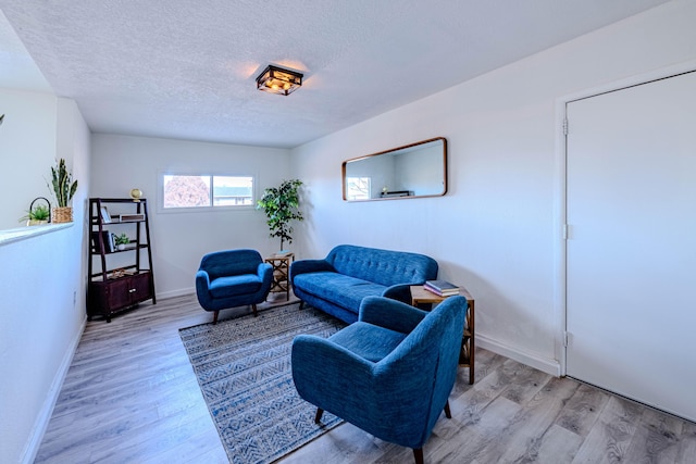 living room featuring a textured ceiling, wood finished floors, and baseboards