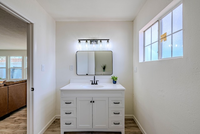 bathroom with baseboards, wood finished floors, and vanity