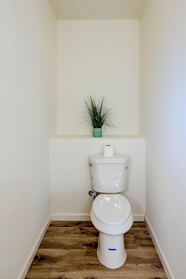 bathroom with baseboards, toilet, and wood finished floors