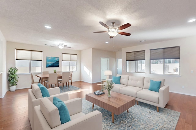 living room featuring hardwood / wood-style flooring, a textured ceiling, and ceiling fan