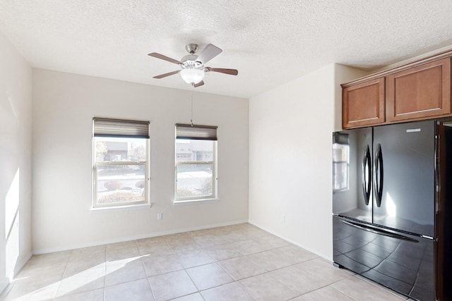 kitchen featuring black refrigerator, light tile patterned floors, a textured ceiling, and ceiling fan