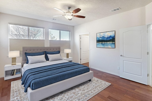 bedroom with a textured ceiling, dark hardwood / wood-style floors, and ceiling fan