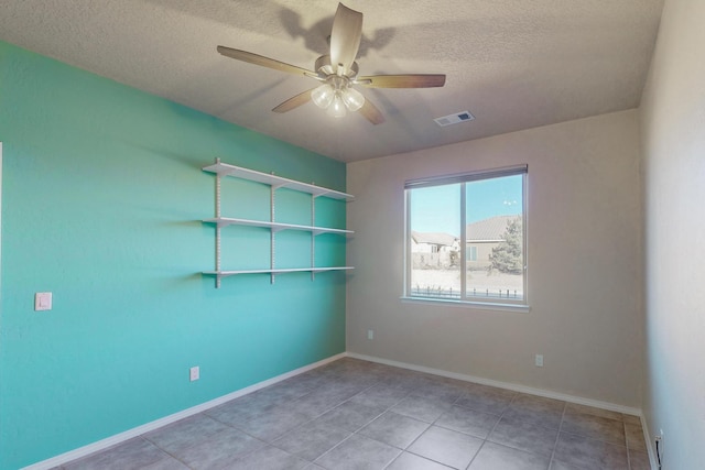 empty room with a textured ceiling, tile patterned floors, and ceiling fan