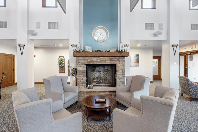 carpeted living room featuring a towering ceiling and a stone fireplace