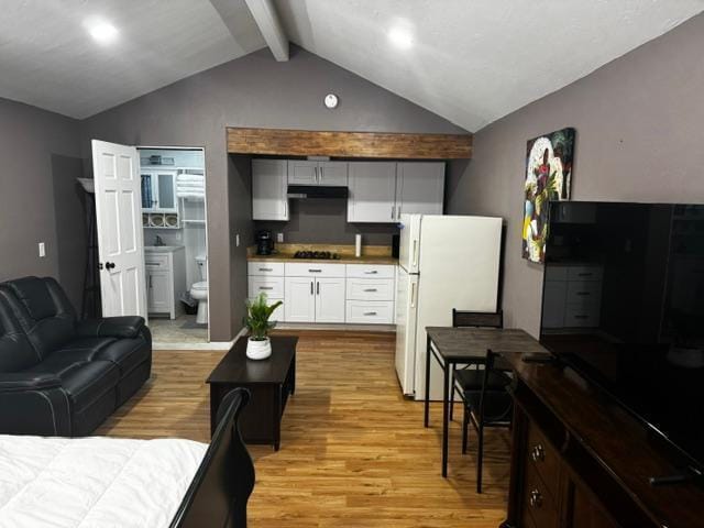 interior space with white fridge, exhaust hood, white cabinets, light hardwood / wood-style flooring, and lofted ceiling with beams