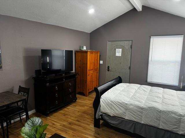 bedroom featuring light hardwood / wood-style flooring and lofted ceiling with beams