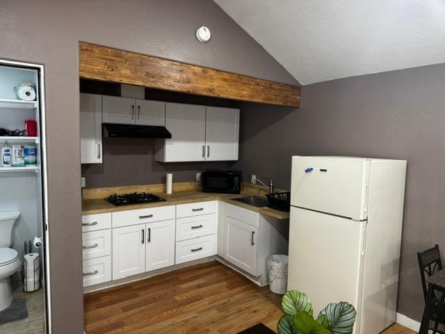 kitchen with vaulted ceiling, black appliances, sink, white cabinetry, and dark hardwood / wood-style flooring