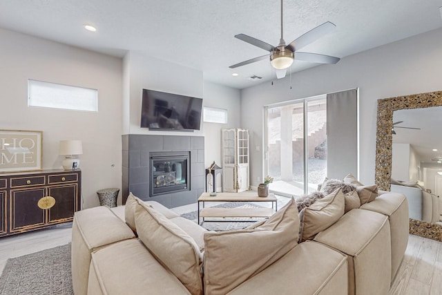 living room featuring a fireplace, light hardwood / wood-style floors, and ceiling fan