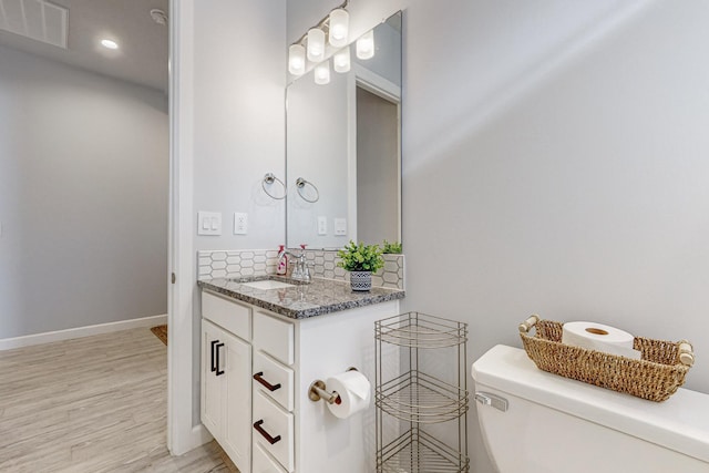 bathroom featuring vanity, backsplash, hardwood / wood-style flooring, and toilet