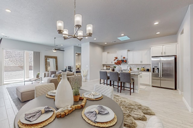 dining room featuring ceiling fan, sink, light hardwood / wood-style floors, and a textured ceiling