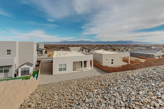 back of property with a mountain view and a patio