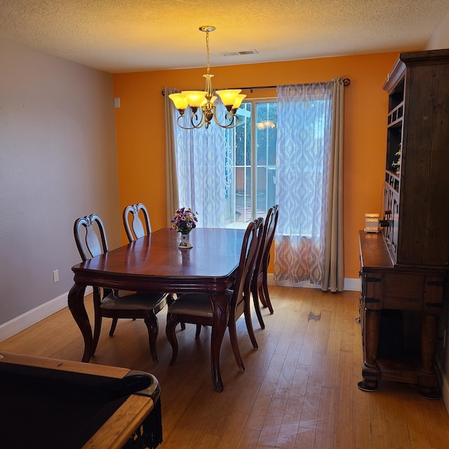 dining room featuring hardwood / wood-style flooring, a textured ceiling, and a chandelier