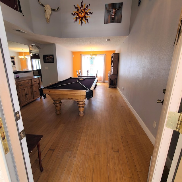 rec room featuring a towering ceiling, billiards, a chandelier, and light hardwood / wood-style flooring