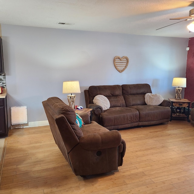 living room with a textured ceiling, light hardwood / wood-style floors, and ceiling fan