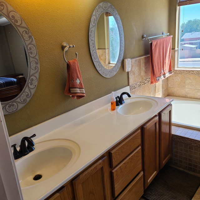 bathroom featuring a relaxing tiled tub and vanity