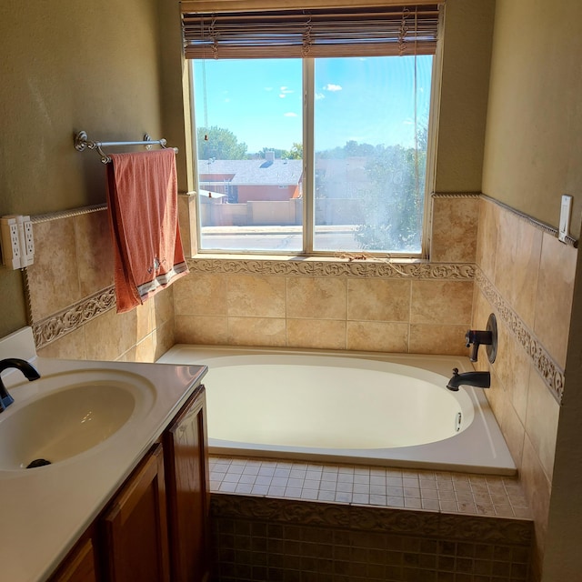 bathroom featuring tiled tub, vanity, and plenty of natural light