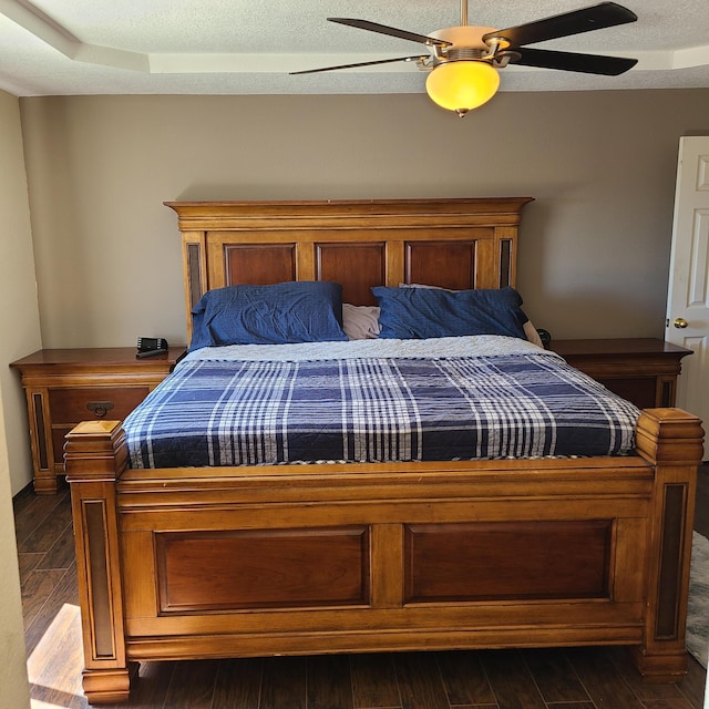 bedroom featuring a raised ceiling, dark hardwood / wood-style floors, and ceiling fan