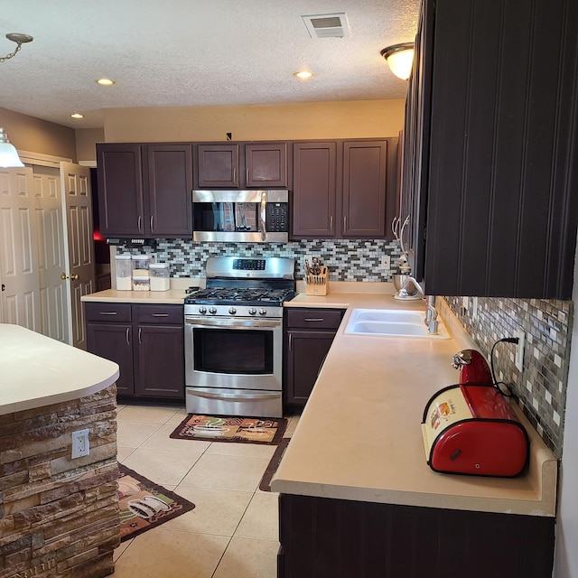 kitchen featuring light tile patterned floors, sink, appliances with stainless steel finishes, hanging light fixtures, and dark brown cabinetry