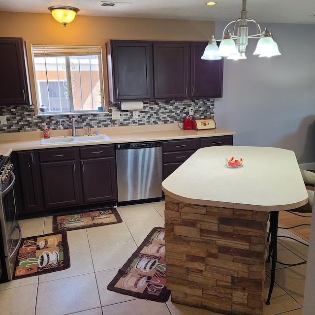 kitchen featuring light tile patterned flooring, sink, hanging light fixtures, appliances with stainless steel finishes, and decorative backsplash