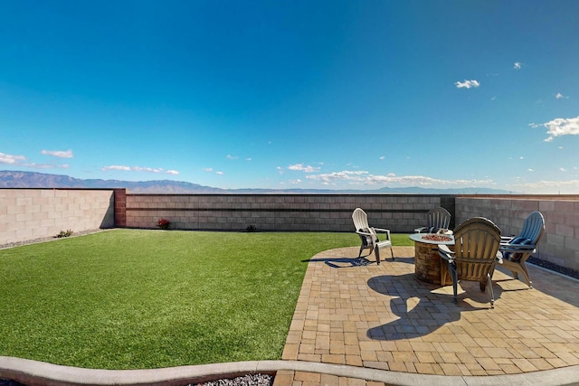 view of yard featuring a patio area, a mountain view, and a fire pit