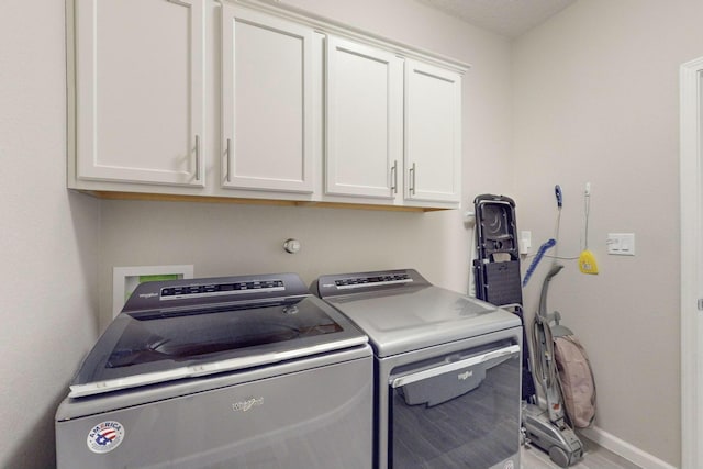 clothes washing area with cabinets, wood-type flooring, and washing machine and dryer