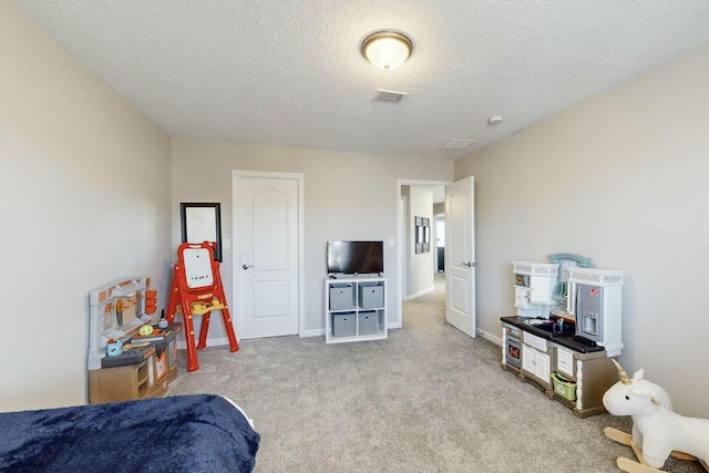 recreation room featuring a textured ceiling and light carpet