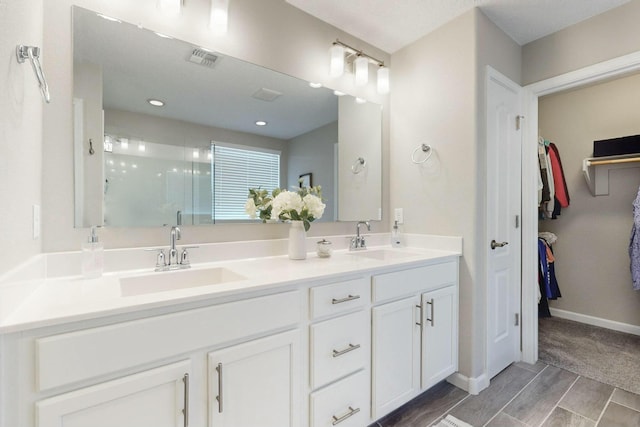 bathroom featuring a shower with door and vanity