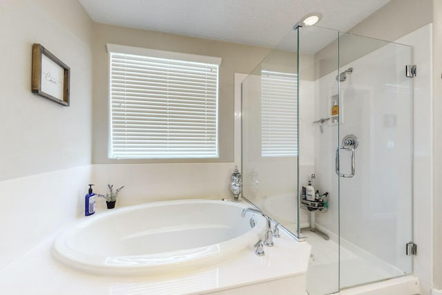 bathroom featuring a textured ceiling and shower with separate bathtub