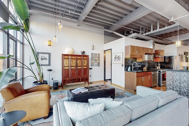 living room featuring sink, beamed ceiling, and a high ceiling