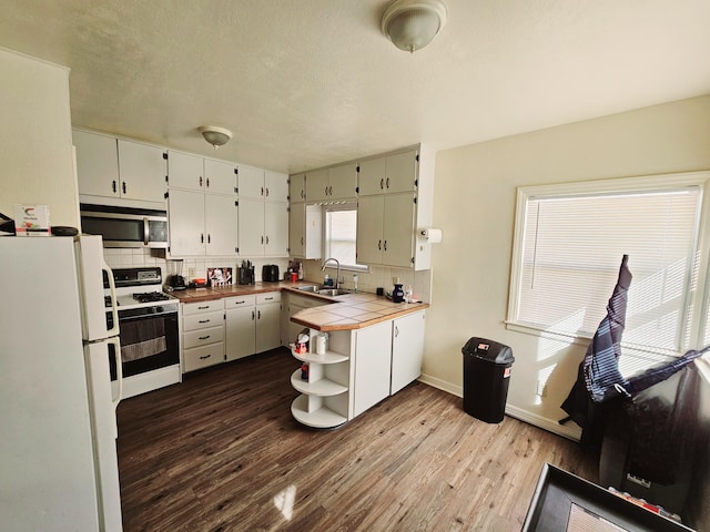 kitchen featuring white appliances, white cabinets, tile counters, sink, and light wood-type flooring