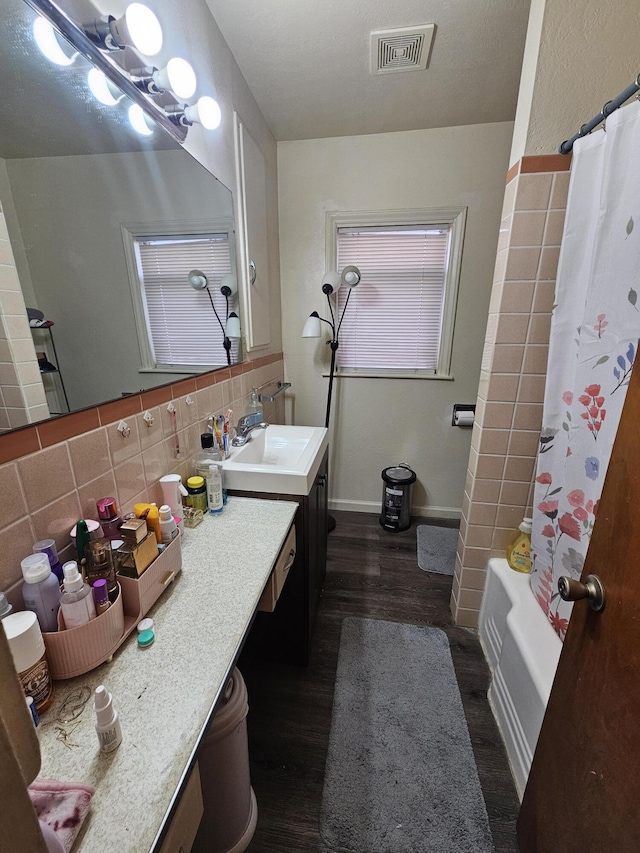 bathroom featuring vanity, tile walls, wood-type flooring, decorative backsplash, and shower / tub combo with curtain