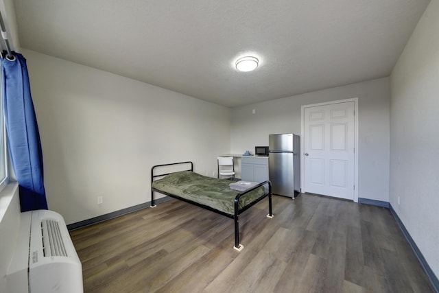 bedroom featuring a textured ceiling, hardwood / wood-style floors, and stainless steel refrigerator