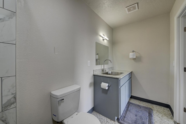 bathroom featuring a textured ceiling, toilet, and vanity