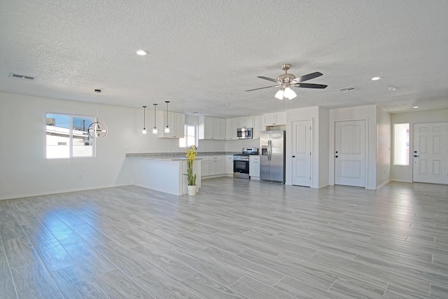 unfurnished living room featuring ceiling fan, plenty of natural light, a textured ceiling, and light hardwood / wood-style flooring