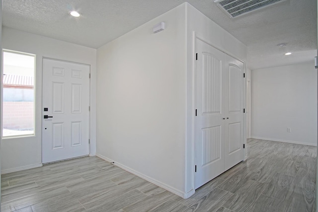 foyer entrance with light wood-type flooring and a textured ceiling