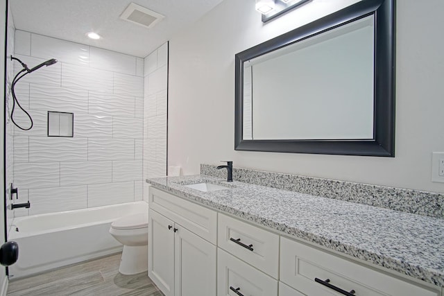 full bathroom with toilet, vanity, wood-type flooring, and tiled shower / bath