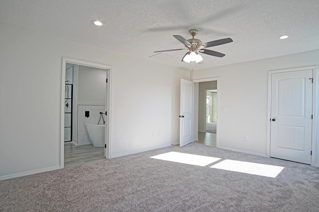 unfurnished bedroom with ceiling fan, light colored carpet, connected bathroom, and a textured ceiling