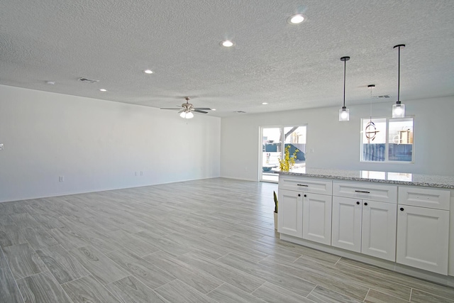 kitchen featuring light stone countertops, a textured ceiling, white cabinets, decorative light fixtures, and ceiling fan